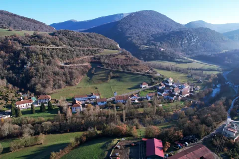 Vista aerea de Aribe con rio, montes boscosos y casas tradicionales dispersas en el valle pirenaico.
