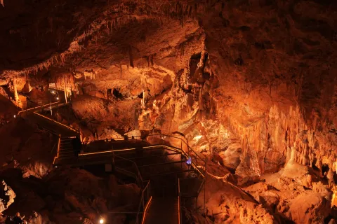 Cuevas de Mendukilo por dentro, con estalactitas y estalacmitas alumbradas con luces anaranjadas.
