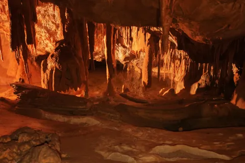 Cuevas de Mendukilo por dentro, con estalactitas y estalacmitas alumbradas con luces anaranjadas.