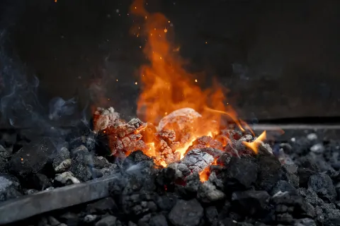 Fuego ardiente con brasas y llamas naranjas en asador tradicional vasco de Atrévete a Forja.