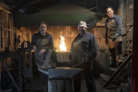 Herrería tradicional en Atrevete a Forjar con maestros profesionales junto a horno de forja encendido y yunque de hierro.