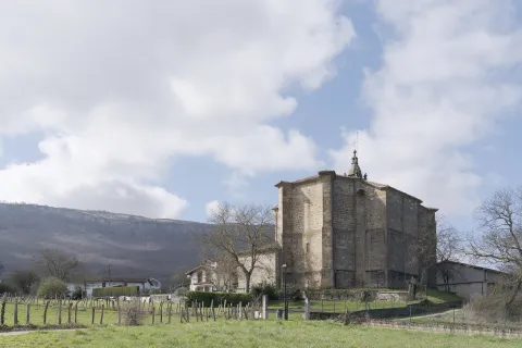 Iglesia de piedra con campanario en Iturmendi, rodeada de prados y montes.
