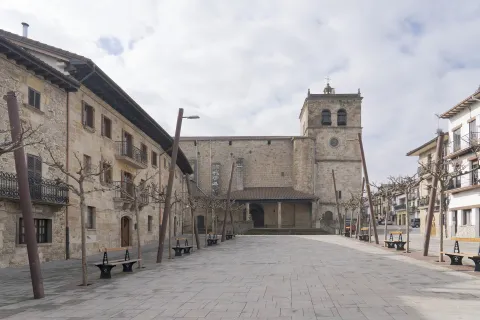 Plaza de Lakuntza con iglesia de piedra, casas tradicionales y árboles desnudos.