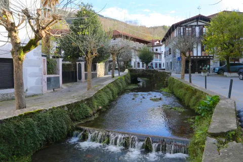 Rio atraviesa el pueblo de Lesaka con casas de piedra y torre a los lados.