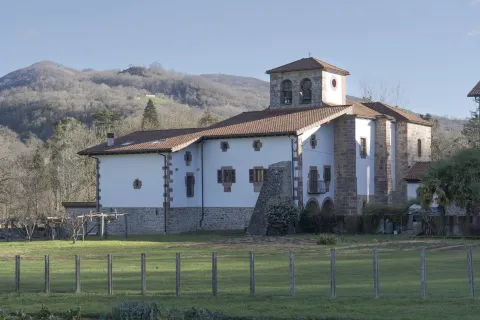 Iglesia parroquial con campanario de piedra blanca, reodeada de un prado verde en Oieregi.