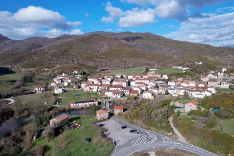 Vista aerea del pueblo de Oroz-Betelu rodeado de montes, casas con tejados rojos y prados verdes.