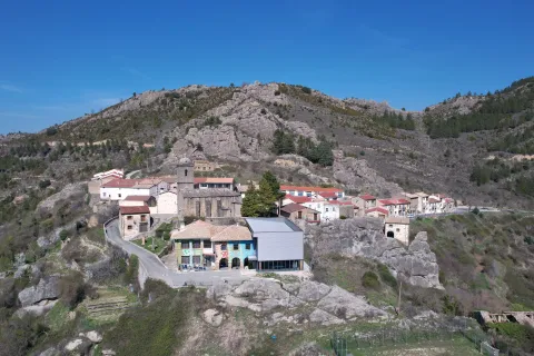 Petilla de Aragón vista aérea con iglesia y casas entre acantilados rocosos y bosque de pinos.