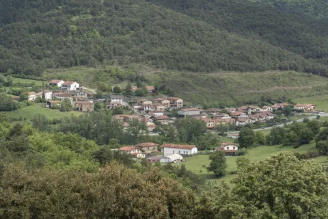 Vista general del pueblo de Urdaniz en el Pirineo navarro, con casas dispersas rodeadas de montes boscosos.