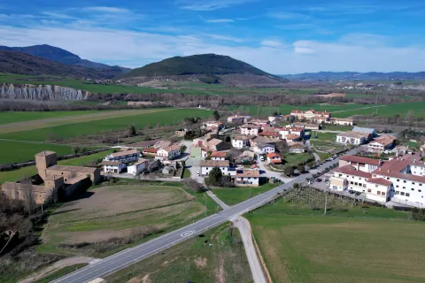 Pueblo de Urraul Bajo visto desde el aire con castillo medieval, caseríos dispersos y campos verdes.