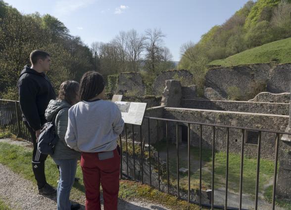 Tres personas miran el cartel informativo de las ruinas de la Fabrica de Armas de Orbaizeta.