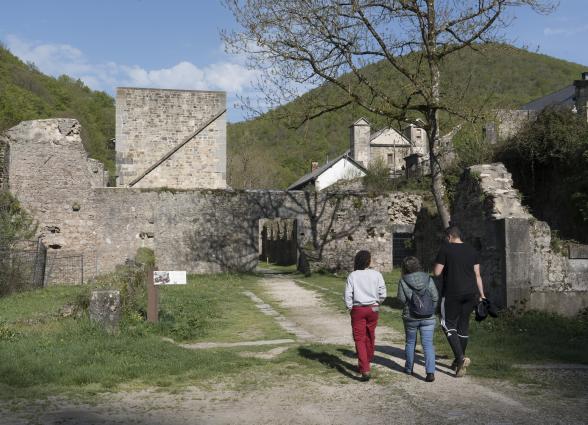 Tres personas caminan hacia la Fabrica de Armas de Orbaizeta.