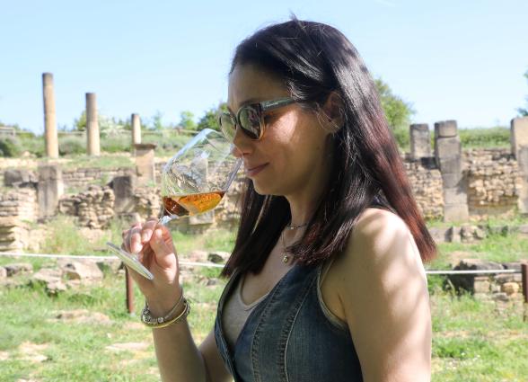 Mujer degustando vino de la Bodega Eslava con yacimiento de Santa Criz de Eslava al fondo.