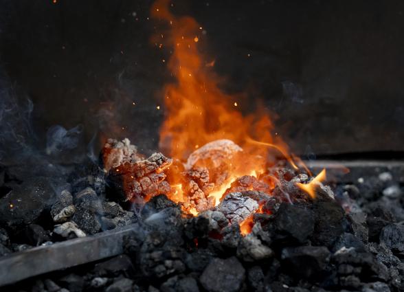 Fuego ardiente con brasas y llamas naranjas en asador tradicional vasco de Atrévete a Forja.