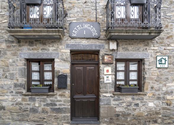 Fachada de piedra de casa rural Katalingarde en Isaba, Pirineo de Navarra, con balconadas de hierro forjado y puerta de madera.