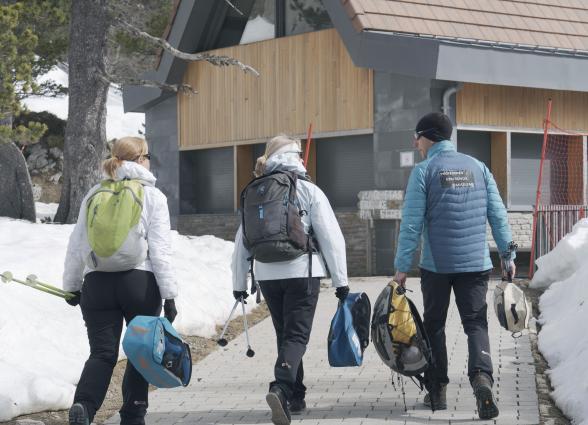 Tres senderistas con mochilas y raquetas de nieve caminan hacia refugio en estación de Larra-Belagua, Pirineo de Navarra.