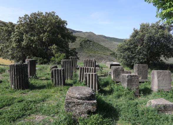 Ruinas de columnas de piedra en Santa Criz de Eslava con valle verde y montañas al fondo bajo cielo despejado.