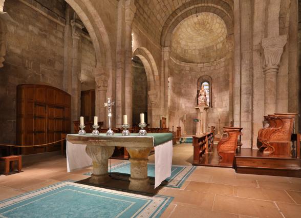 Interior de iglesia en Monasterio de Leyre con naves abovedadas, altar y arquitectura románica de piedra sillar.