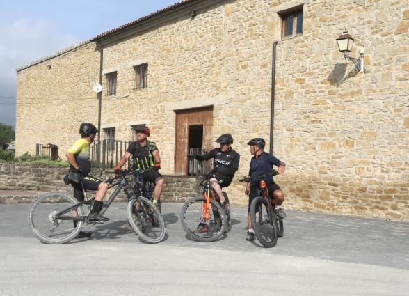 Grupo de ciclistas con bicicletas de montaña frente a edificio de piedra, Bodega Eslava.