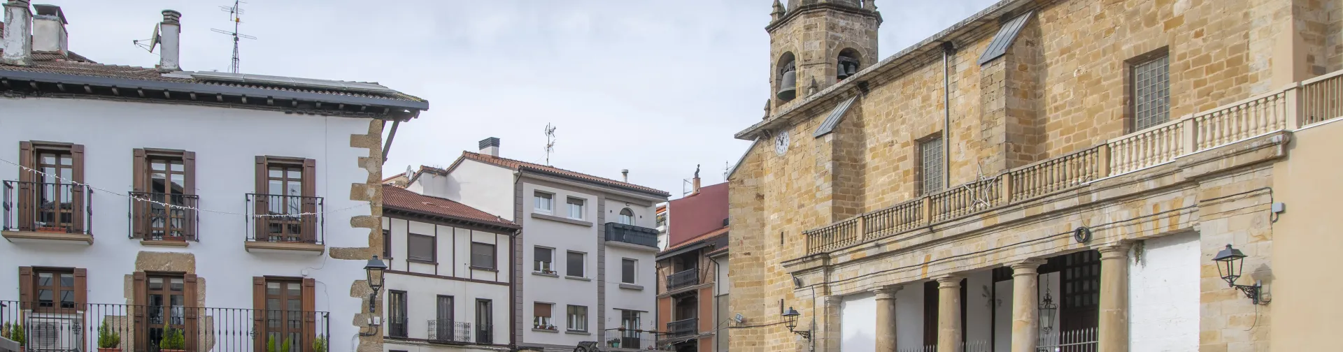 Calle empedrada del casco antiguo de Alsasua con edificios de piedra y la iglesia a un lado.
