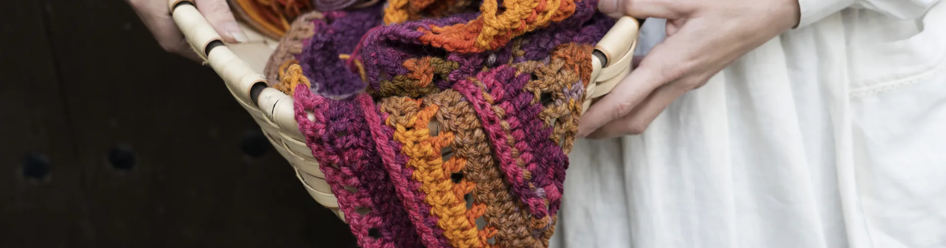 Detalle de manos sosteniendo cesta con lana de colores vibrantes en El Gantxillo de Mari.