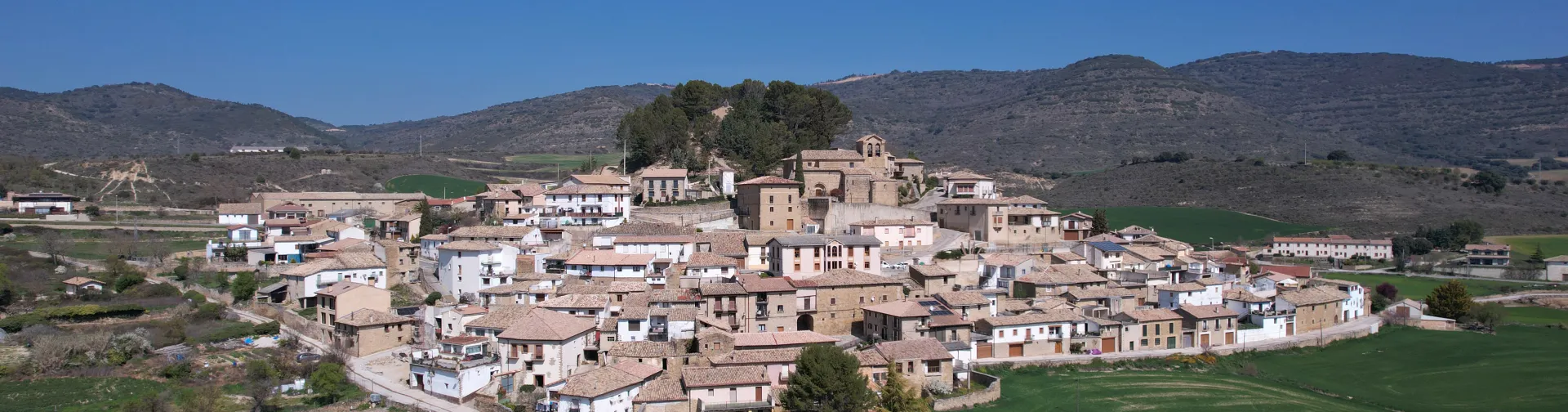 Pueblo de Eslava con iglesia, casas de piedra y campos cultivados alrededor.