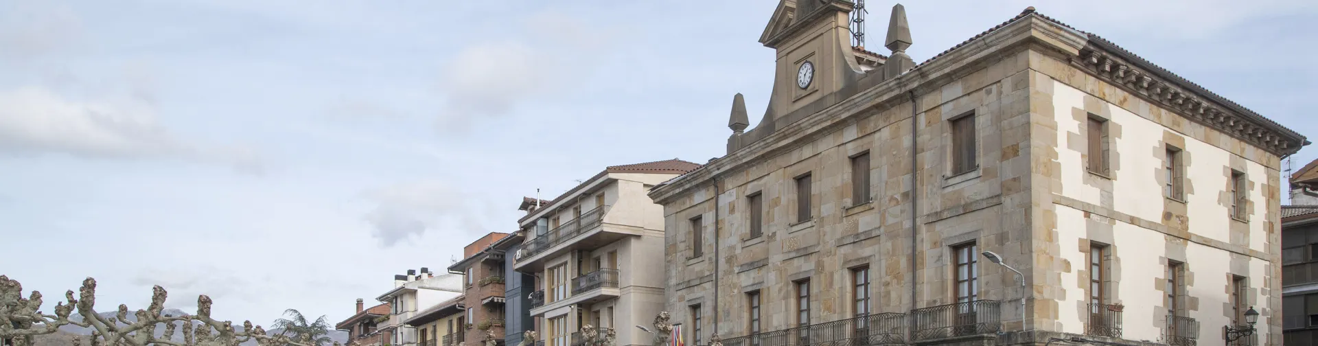Plaza de Etxarri Aranaz con edificio consistorial de piedra y reloj.