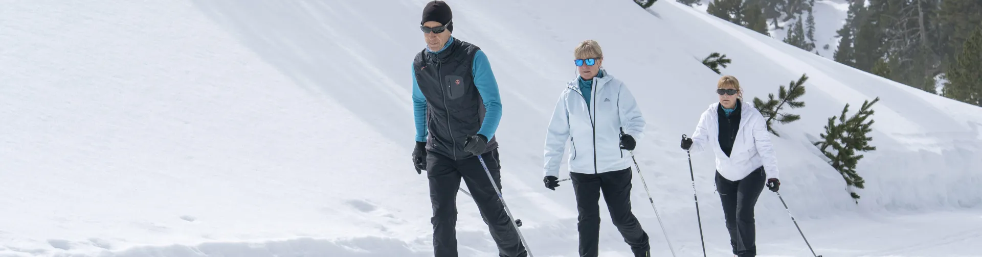 en raquetas de nieve recorren la pendiente nevada de Larra-Belagua en el Pirineo navarro, con abetal y hayedo al fondo.
