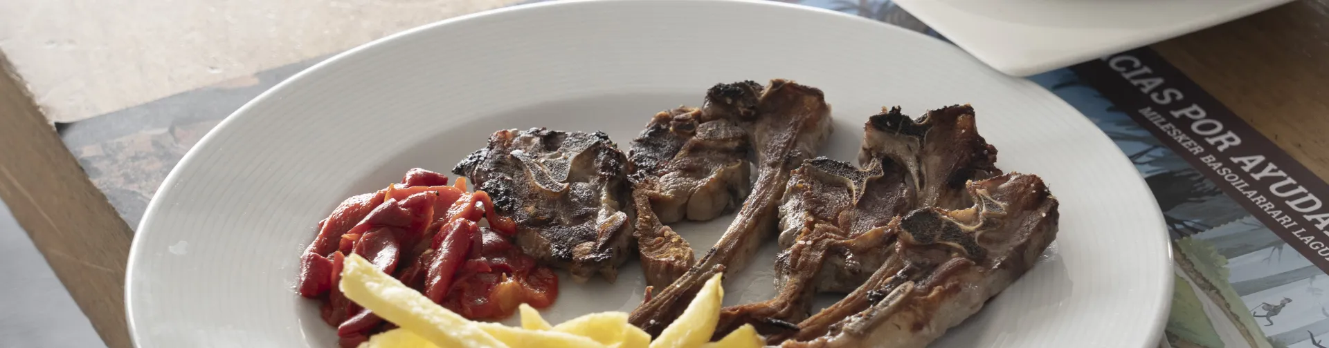 Plato de carne asada con patatas fritas y pimientos en restaurante de Larra-Belagua, Pirineo navarro.