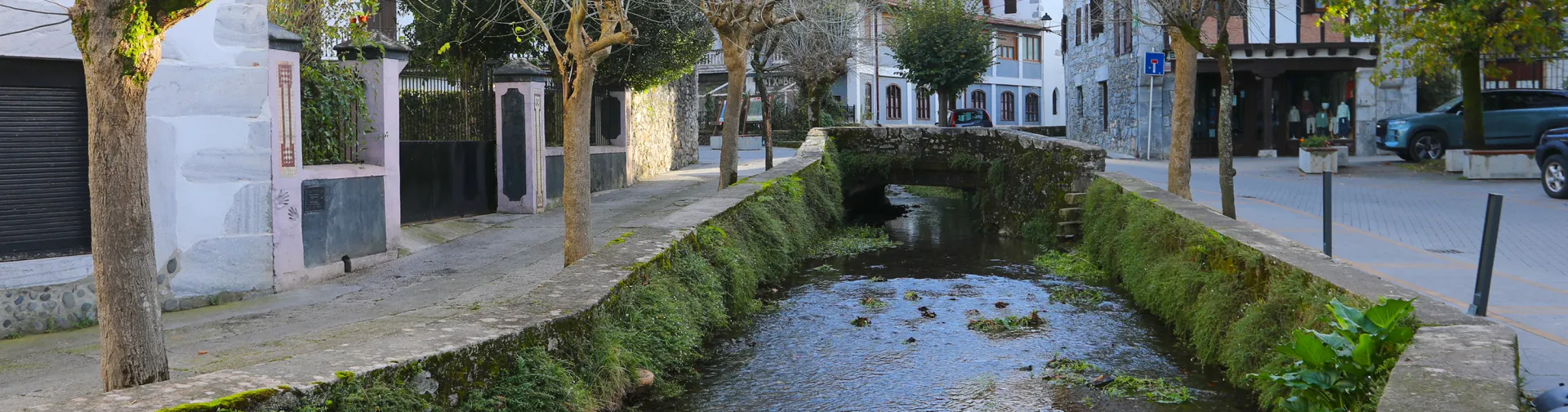 Rio atraviesa el pueblo de Lesaka con casas de piedra y torre a los lados.
