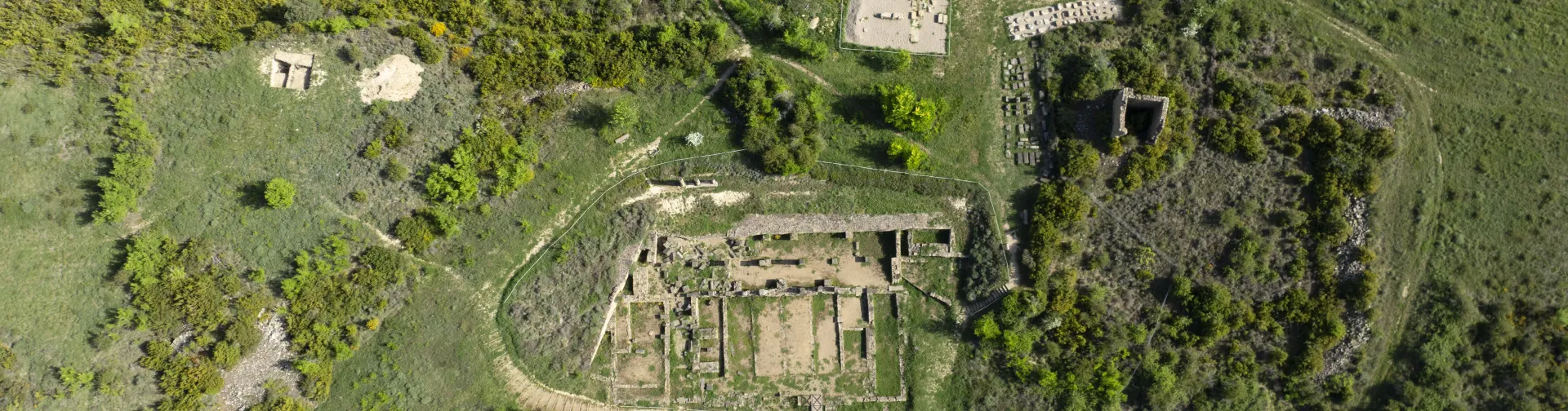 Vista aerea de las ruinas de Santa Criz de Eslava rodeadas de arboles y vegetacion, sendero y construcciones anexas.