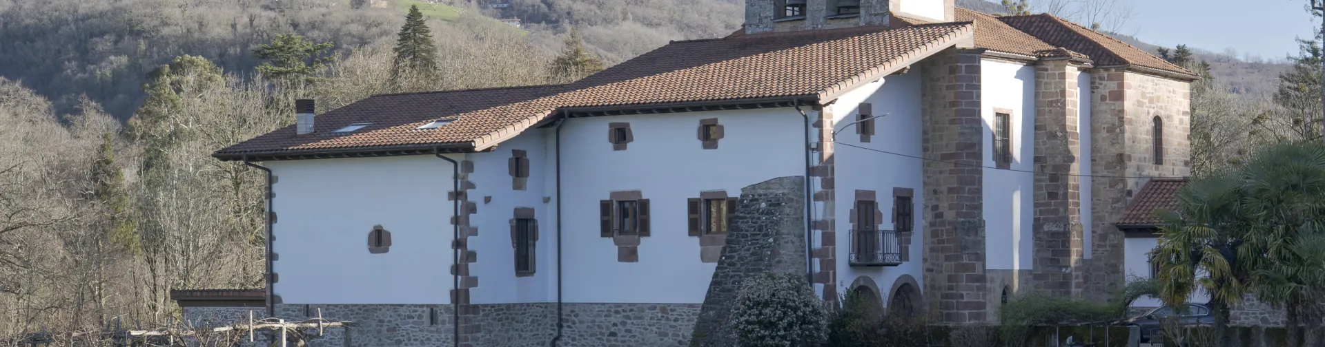 Iglesia parroquial con campanario de piedra blanca, reodeada de un prado verde en Oieregi.