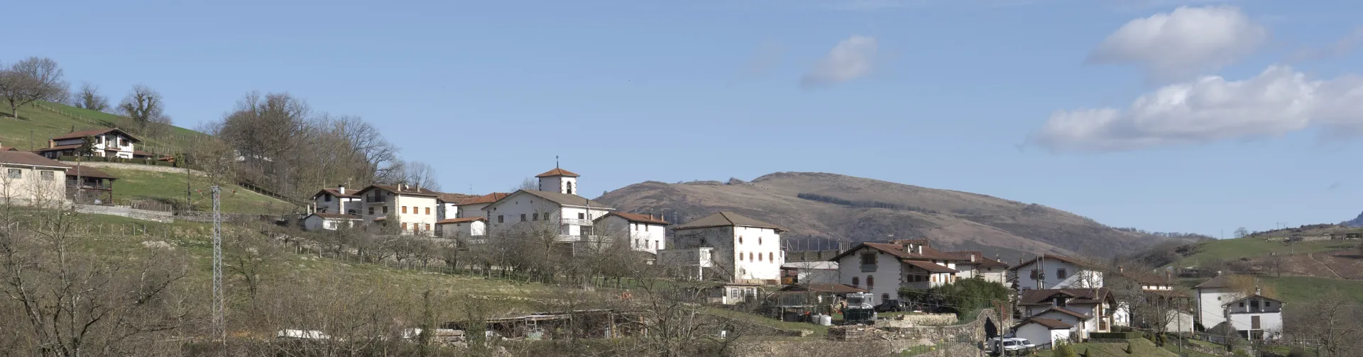 Panorámica de Oitz con pueblo disperso en montañas, prados, bosques y casas tradicionales.