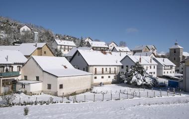 Pueblo de Abaurrea Alta nevado con casas de piedra y tejados blancos, iglesia al fondo.