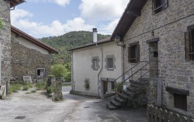Complejo de edificios tradicionales de piedra en Agorreta, Pirineo navarro, con arquitectura rural pirenaica y bosque al fondo.