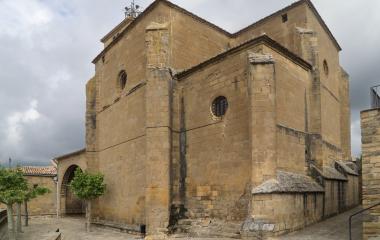 Iglesia rural de piedra arenisca en Aibar, con torre campanario cuadrada de estilo medieval.