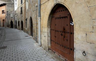 Calle empedrada de Aoiz con casas de piedra y puerta ojival de madera con clavos decorativos.