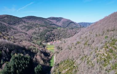 Pueblo de Arce en valle verde rodeado de montes boscosos y prados naturales.
