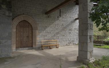 Portada de iglesia medieval en piedra , banco de madera y vegetación en Ardaitz, Pirineo navarro.