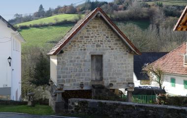 Un horreo, construcción agrícola tradicional, de piedra en Aria, en paisaje pirenaico de monte verde.