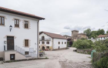 Plaza de Arrieta con caseríos de piedra blanca, iglesia parroquial al fondo, arquitectura rural pirenaica navarra.