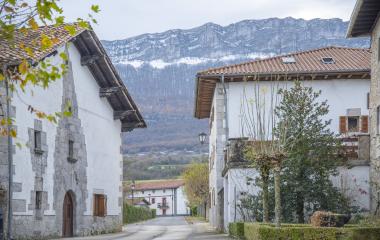 Calle principal de Arakil con casas tradicionales vascas blancas a los lados y el monte detrás.