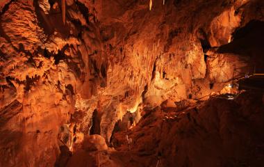 Cuevas de Mendukilo por dentro, con estalactitas y estalacmitas alumbradas con luces anaranjadas.