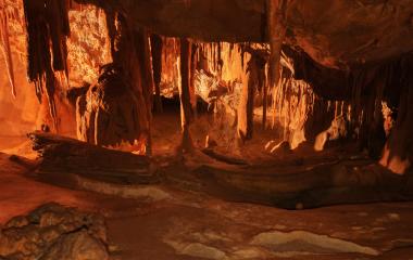 Cuevas de Mendukilo por dentro, con estalactitas y estalacmitas alumbradas con luces anaranjadas.