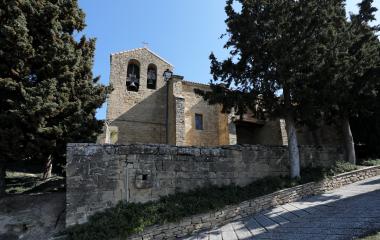Iglesia de piedra con campanario de dos vanos en Ezprogui, bajo cielo despejado.