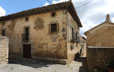 Casa de piedra arenisca en Gallipienzo con escudo heráldico labrado y balconadas de hierro forjado.