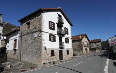 Casa tradicional de piedra y blanca en Garde con balconadas de hierro forjado y tejado de teja roja.