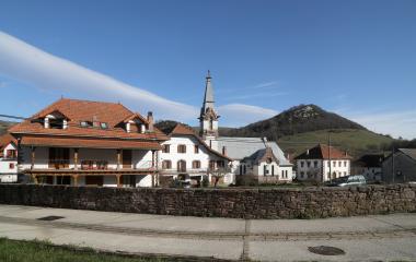 Pueblo de Garralda con iglesia de campanario puntiagudo, casas de piedra y tejados rojos.