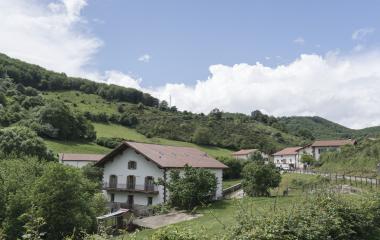 Caseríos tradicionales en valle de Iragi, rodeados de prados verdes y bosque de media montaña en el Pirineo Navarro.