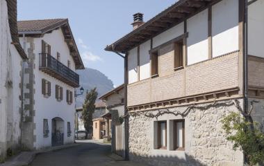Calle empedrada de Irañeta con casas de piedra y fachadas blancas.