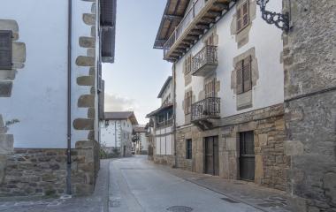 Calle peatonal empedrada de Ituren con casas de piedra blanca de diversos estilos arquitectónicos.